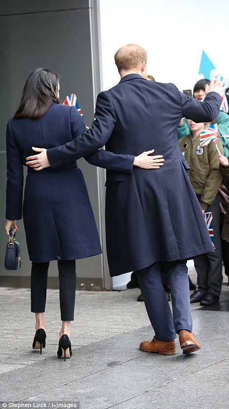 Harry and Meghan put a hand on each other's backs as they wave to the crowds...
