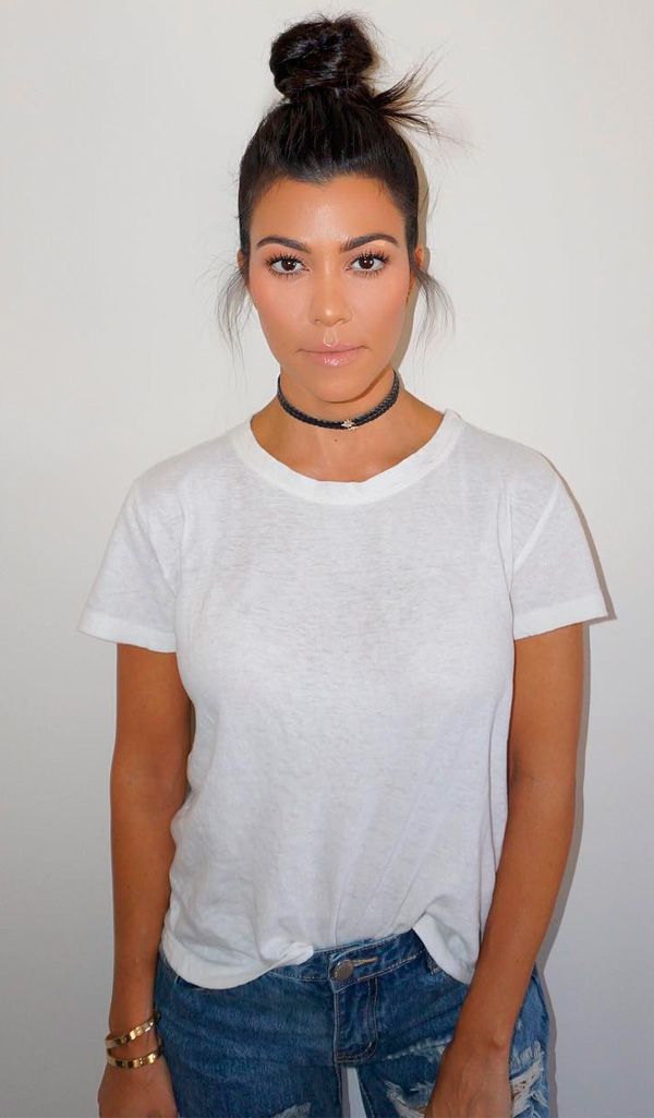 Kourtney Kardashian em estilo básico, com camiseta branca, calça jeans rasgada...