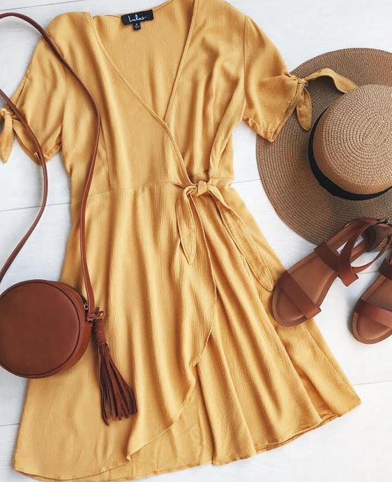 Golden yellow wrap dress with leather accessories and a wide-brimmed hat. Ultima...