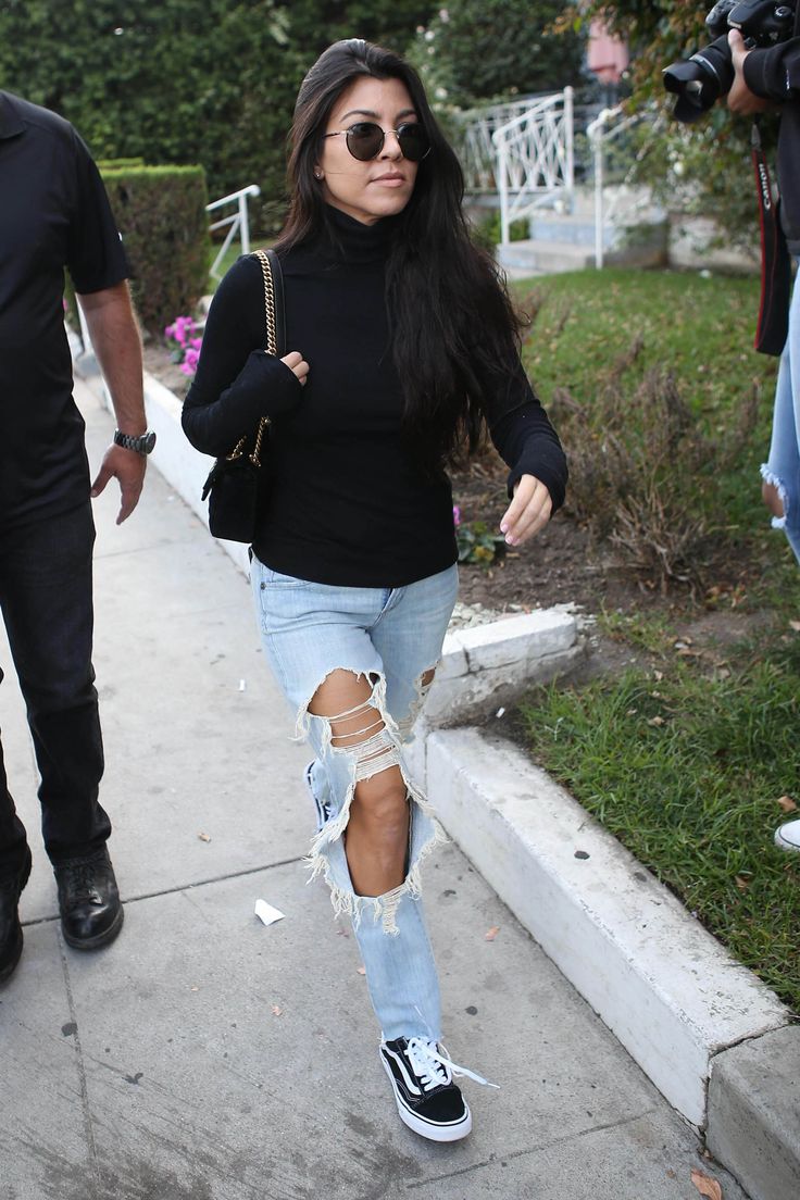 Kourtney Kardashian in a black sweater, ripped jeans and Vans sneakers.